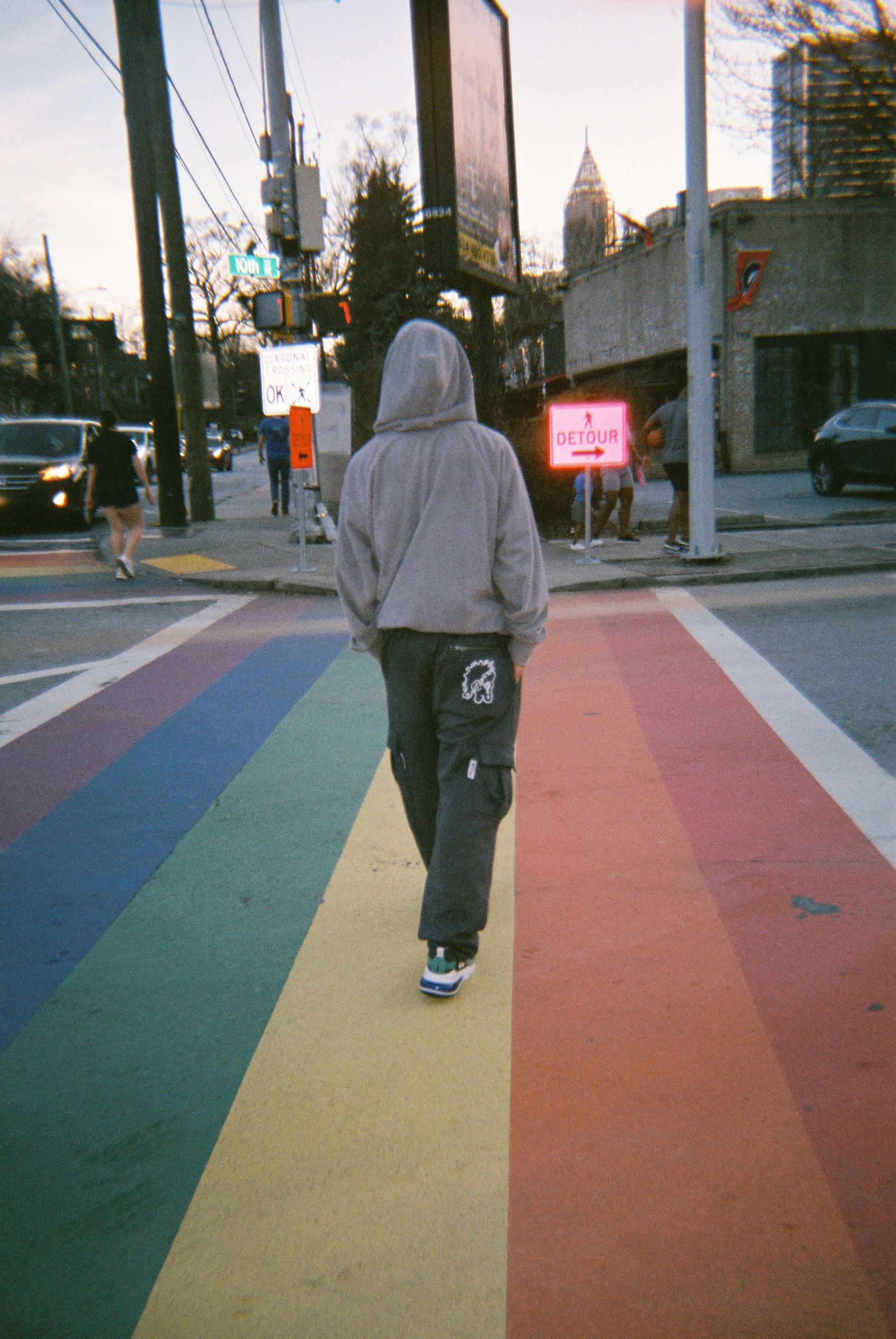 Model wearing Vibrance Cargo Pants Sweatpants and Hoodie on rainbow road